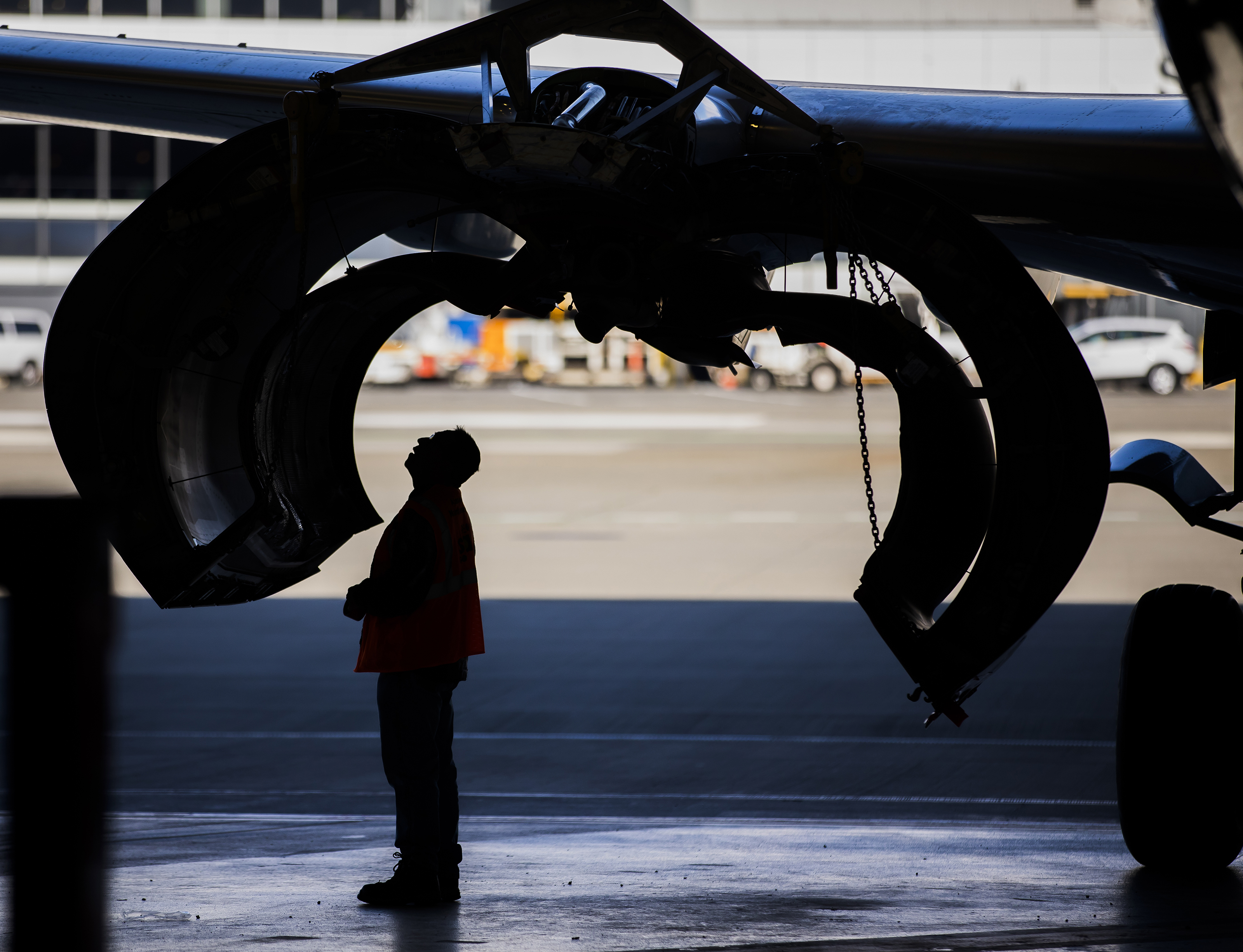 Silhoutte of man standing underneath plane wing