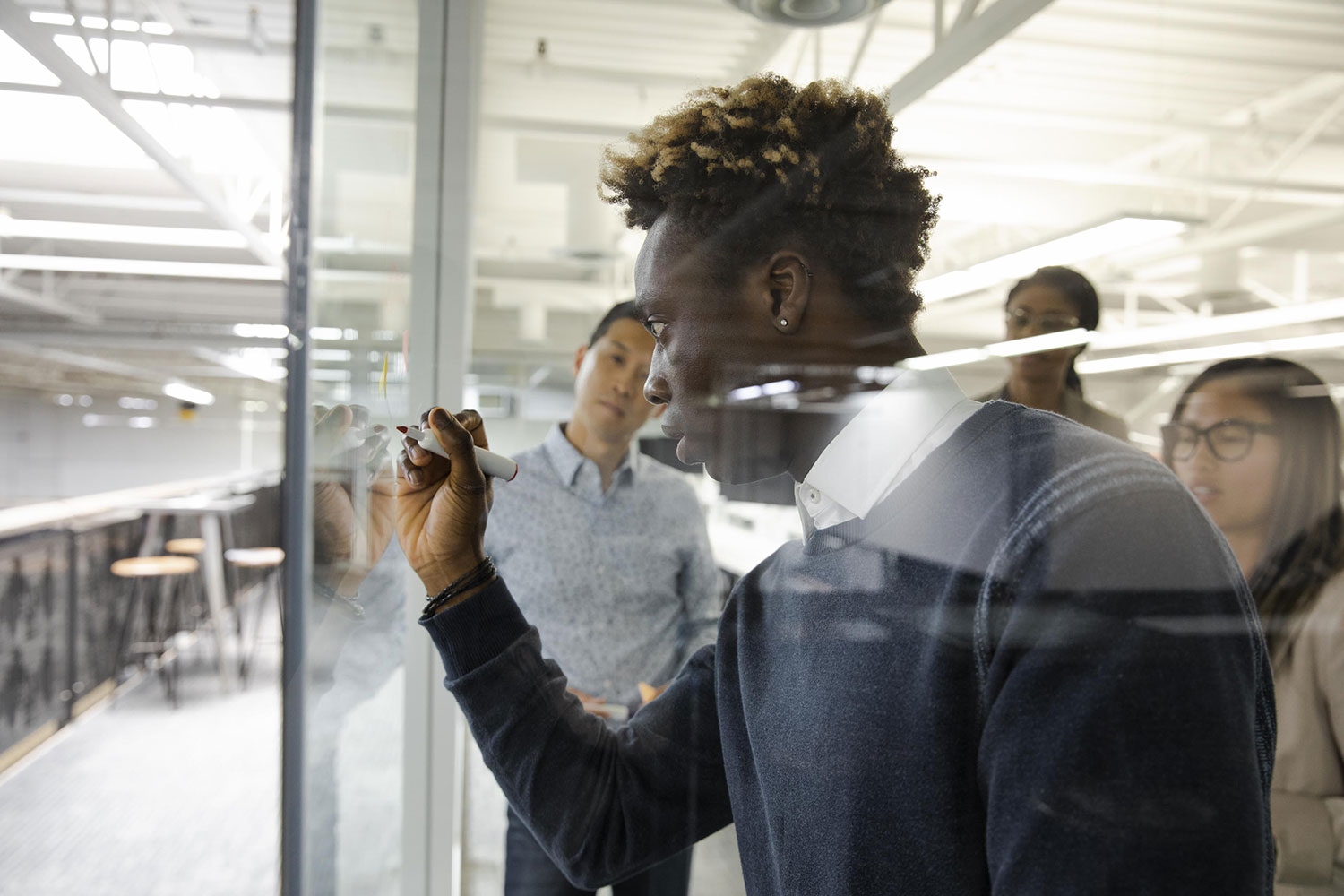 Man writing on glass screen during meeting in an open concept office